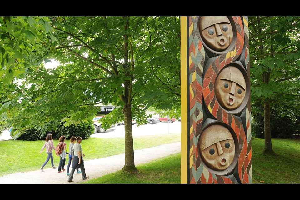 Visitors stroll pass one of the three portals by Musqueam artist Susan Point in Stanley Park. Photo Dan Toulgoet