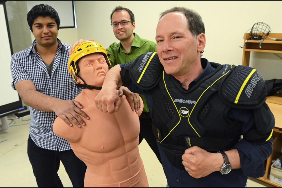 SFU researcher Stephen Robinovitch (right) roughs up a dummy with help from research engineer Colin Russell (middle) and biomedical physiology master’s student Shane Virani (left) at the university’s Injury Prevention and Mobility Laboratory, where the three will study ways to improve hockey pads and boards to reduce head injuries among hockey players.