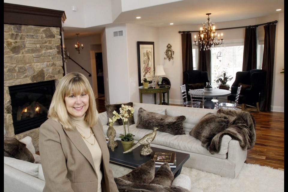 Robin Brechbuhler, owner of Brechbuhler Design, stands inside a living room designed using many different shades of grey.