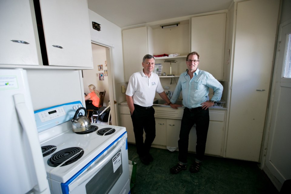 Mark Muldoon, left, executive director of Threshold Housing Society, and Paul Latour of the Hero Work Program, stand in the kitchen of one of four apartments in the complex at Oak Bay Avenue and Davie Street.