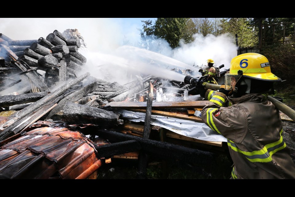 Firefighters Kail Beck, left, and Jordan Eamer battle a fire at an East Sooke family home owned by former Capital Regional District director Brian Henson.
