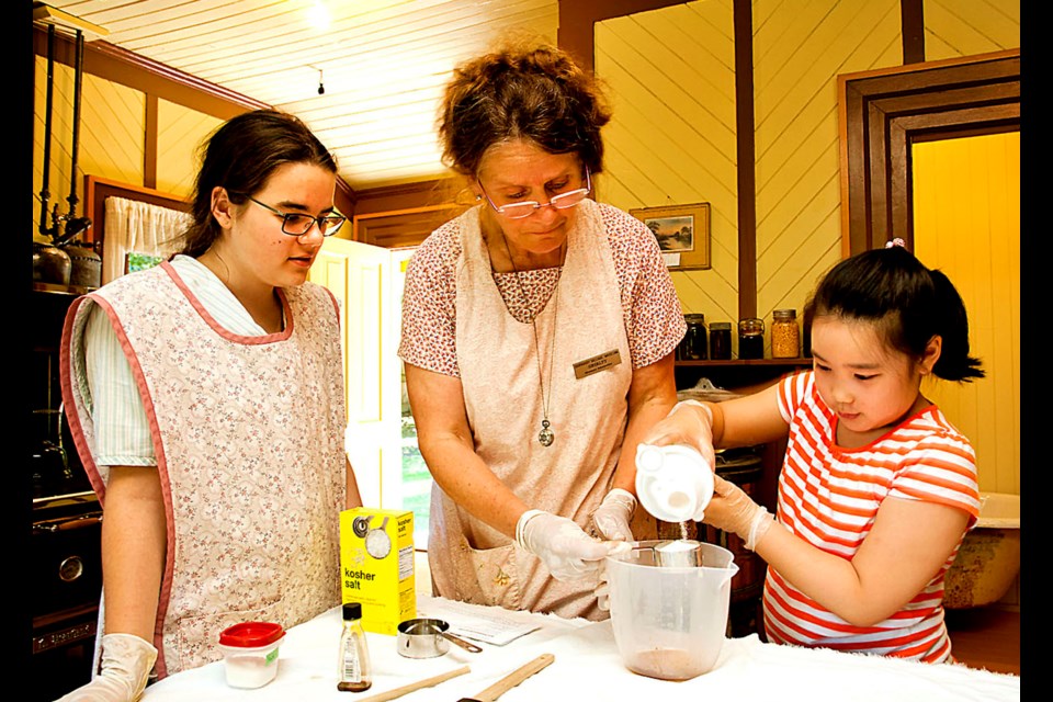 Nine-year-old Elisheba Yoon measures out the sugar for the ice cream mix workshop instructors Bella Urbanowski, left, and Shirley McGrew, centre, watch over. The workshops are open to kids and adults and run every Saturday at the Burnaby Village Museum.