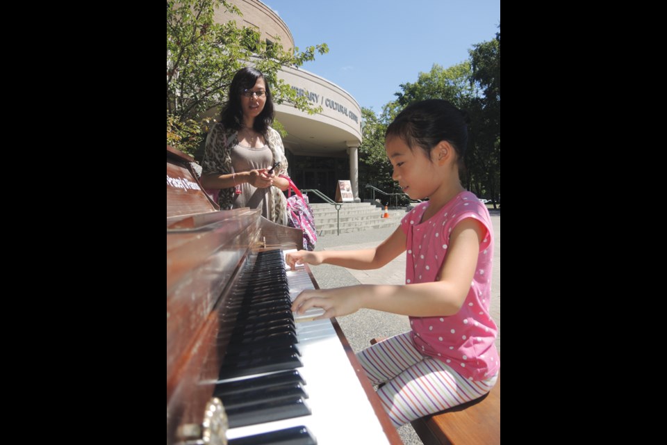 Cici Qin, 7, with mom, Lisa Wang, at the outdoor piano outside the Richmond Cultural Centre. Photo by Christopher Sun/Special to the News