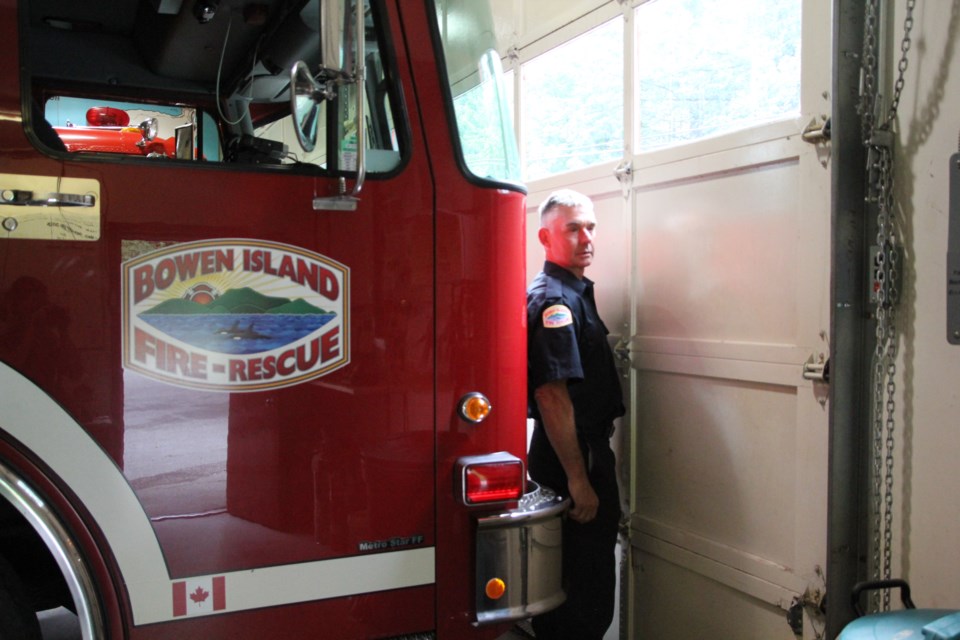Fire chief Ian Thompson standing in front of a fire truck in the fire hall.