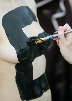 A letter is painted on a participant at the Cadboro Bay beach.