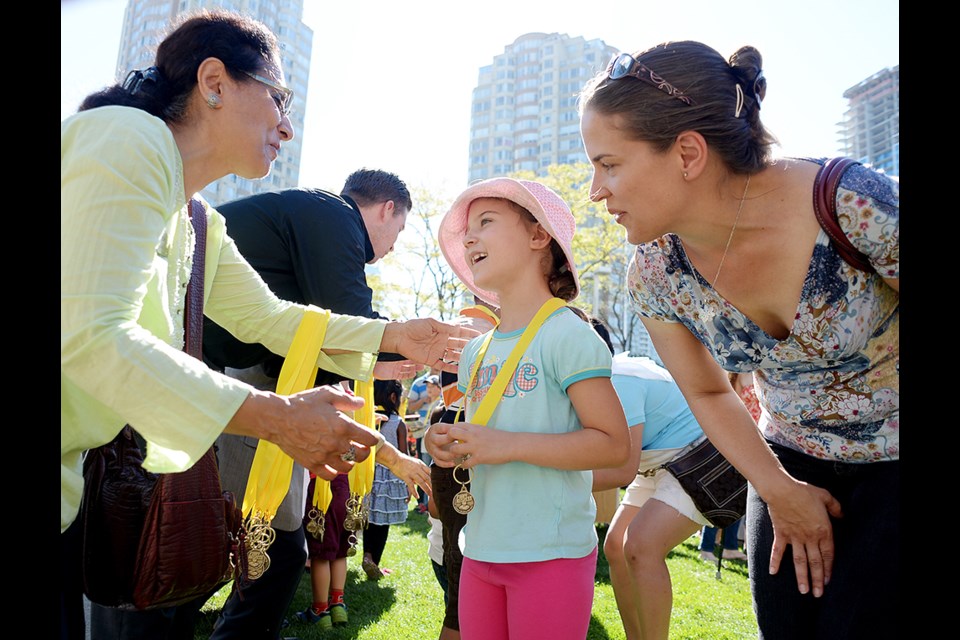 School board chair Baljinder Narang hands out a medal at the library's annual ceremony for the summer reading club. Kids who read (or were read to) for 50 days received medals on Saturday.