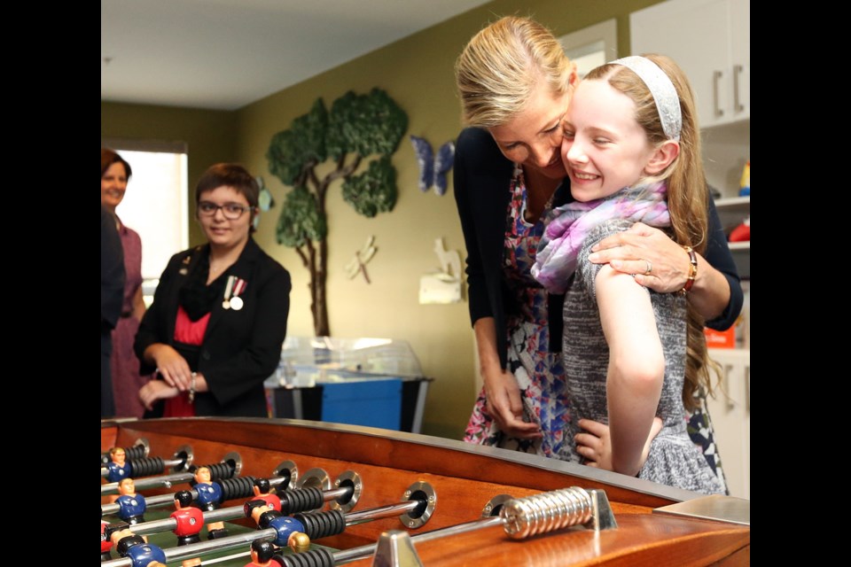 Sophie, the Countess of Wessex, hugs 10-year-old Abigail McCorquodale during a game of foosball while Jeneece Edroff looks on at Jeneece Place on Saturday, Sept. 13, 2014.