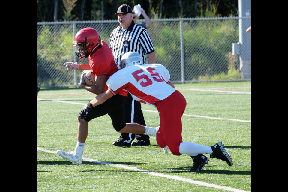 Escaping the grab: A St. Thomas More player, in solid red, tries to escape a Surrey Holy Cross player, last week. STM’s junior varsity football team beat Holy Cross 46-12. The JV Knights are on the road in Surrey this week to face off against Earl Marriott on Wednesday (today).