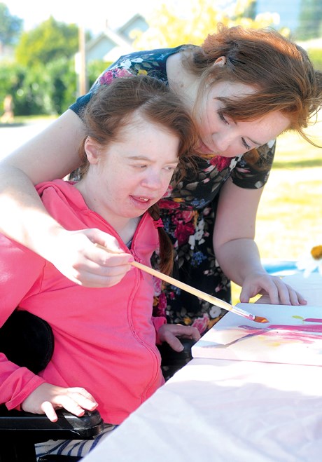 Emily Macdonald helps her sister Cait apply paint to a canvas during an Abled-Art in the Park sessio