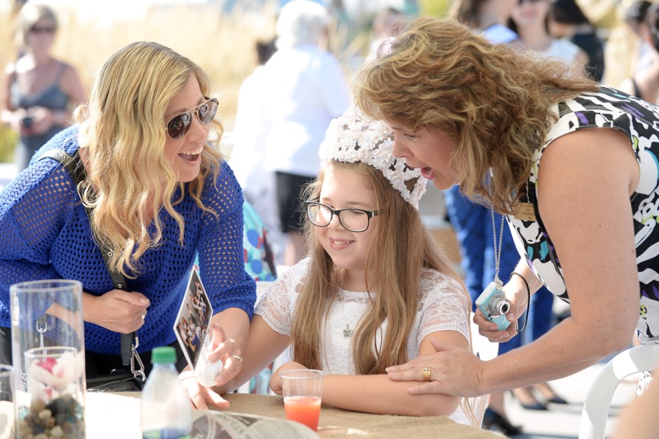Cassidy Tecklenborg, centre, looks at old photographs with her mom Leslie Nichol, left, who was an ambassador and Miss Congeniality in 1993, and Becci Dewinetz, Miss New Westminster 1981, at a recent garden party at Westminster Pier Park. It was one of the events in the Coming Home to Hyack ambassadors’ reunion weekend in New Westminster.