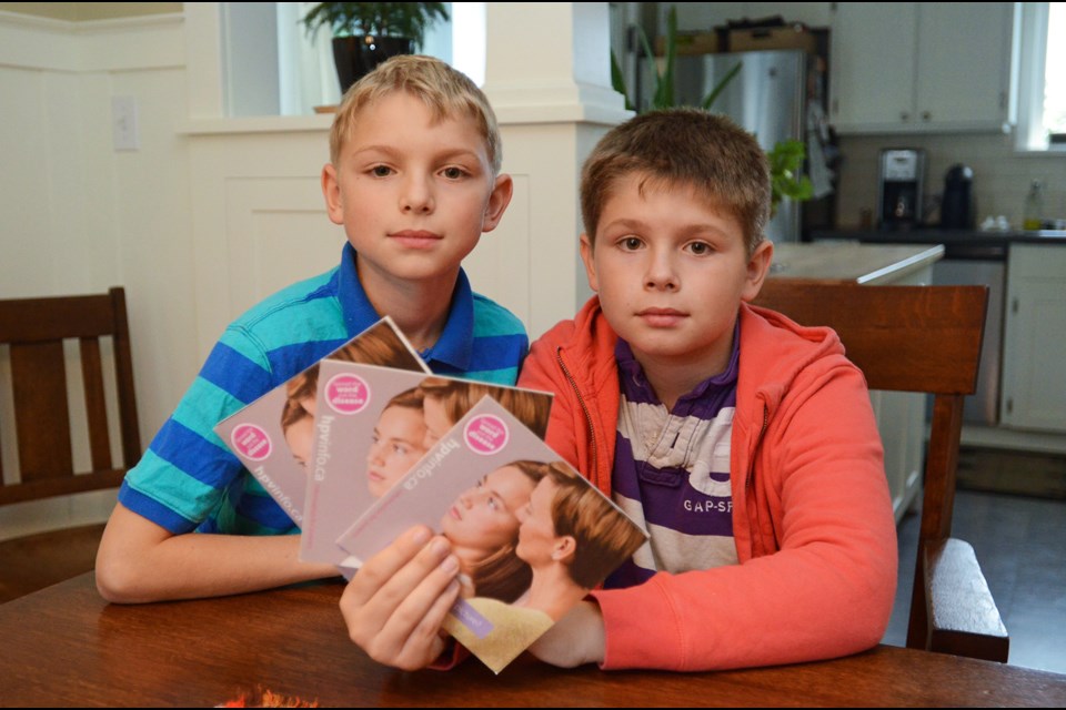 In a 2014 photo, New Westminster sixth graders Nelson and Elliot Roy pose with some girl-centred HPV vaccination pamphlets. The twins, now 13, say health officials will have to work hard to convince boys to get the shot.