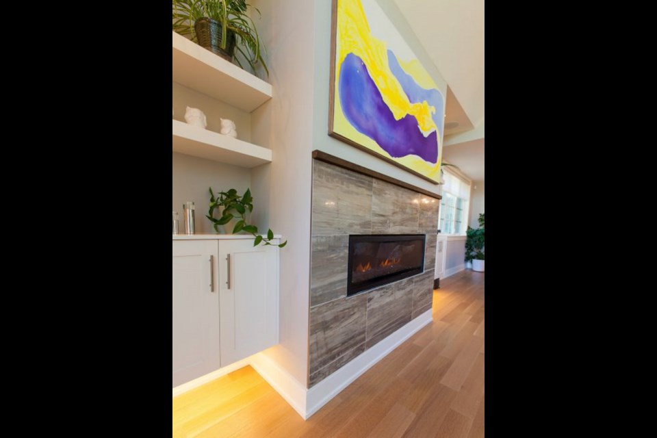 Built-in shelves on either side of the fireplace anchor the interesting feature wall that includes a stone tile, which looks like wood grain. The painting is by Ottawa artist Kerry Milligan-Bendin.