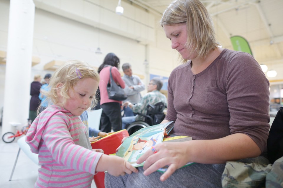 Josie Hindson, 2.5 and her mom Marcela read a book together at the New West Pop-Up Library launch event at River Market on Sunday, Oct. 12.