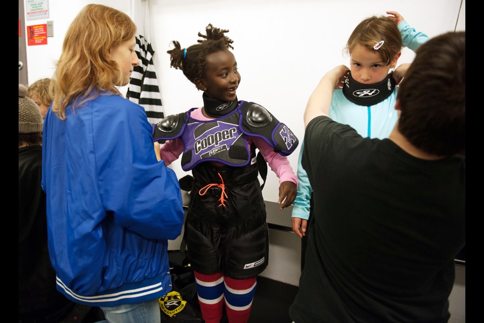 Vancouver Angels goalies Eloise Haliburton, left, and Analise Legge help sisters Aniika Rinas, left, and Alexandra Rinas, suit up for the first time at Killarney Rink for Saturday’s Come Try Hockey Free clinic. The clinic, hosted by the Vancouver Angels (also known as the Killarney Girls Ice Hockey Association) is held several times a year. Photograph by: Rebecca Blissett