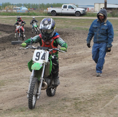A young rider heads to the start line, with his dad following close behind.