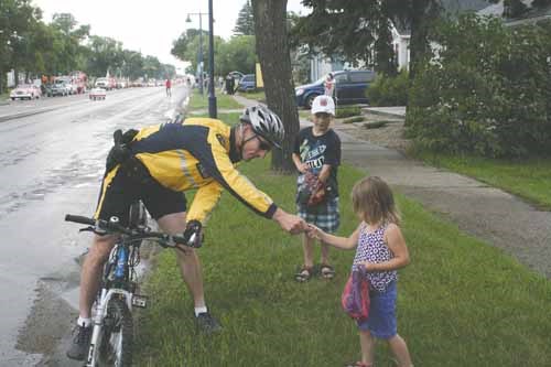 RCMP Cst. Lortie took time in the rain to hand out stickers to Grayson and Sallisa Auger of Yorkton, who were in attendance to watch the Yorkton Exhibition Association Parade Saturday, July 6.