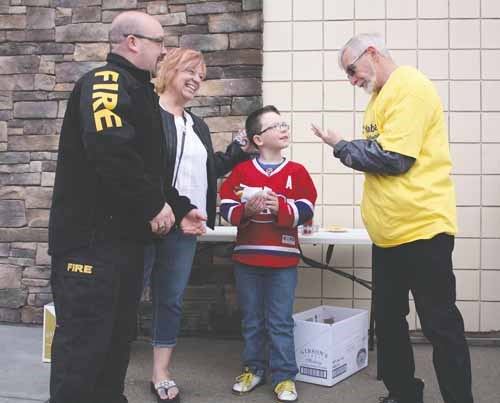 Habitat for Humanity volunteer John Boulton, right, jokes with Fire Chief Trevor Morrisey, his wife Teena and son Trevor Jr. at a Canadian Tire-Habitat barbecue fundraiser April 24. Fundraising is now targeting a 2015 duplex project as the latest home on Roslyn Avenue nears completion.