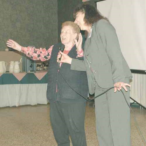 Anna Ingham, a Yorkton District Nursing Home Volunteer, sang and danced &#8220;Robin in the Rain&#8221; at the Sunrise Health Region Volunteer Appreciation Tea. Ingham, a teacher, is 99 years of age and captures the spirit of volunteerism at Sunrise. A total of 2,300 registered volunteers in the health region work in the gift shop, deliver meals on wheels, knit handmade baby hats and do many other important tasks. Volunteers who attended the appreciation event received mini staplers as a gift for being &#8220;staples of the community.&#8221; (Pictured right: Mistress of Ceremonies Karen DeLong, Therapeutic Recreation Department of Yorkton and District Nursing Home.)