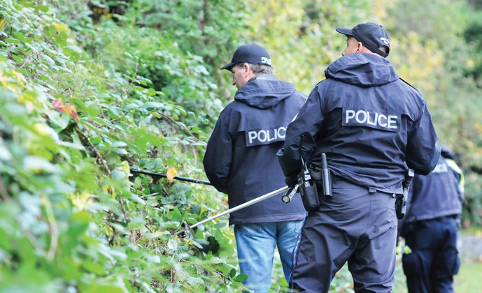 West Vancouver police officers on the scene near West Bay elementary where someone threw two loaded pistols into the bushes Wednesday night.