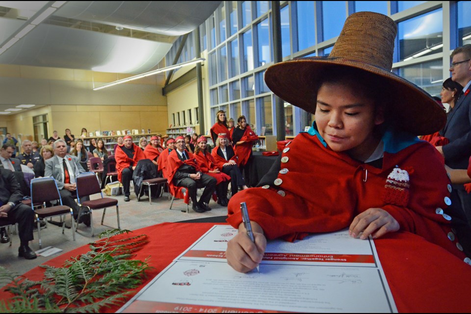 Burnaby Central Grade 10 student Diana Charlie-Iraheta signs the Burnaby school district's second aboriginal education enhancement agreement at a ceremony in her school's library Thursday.