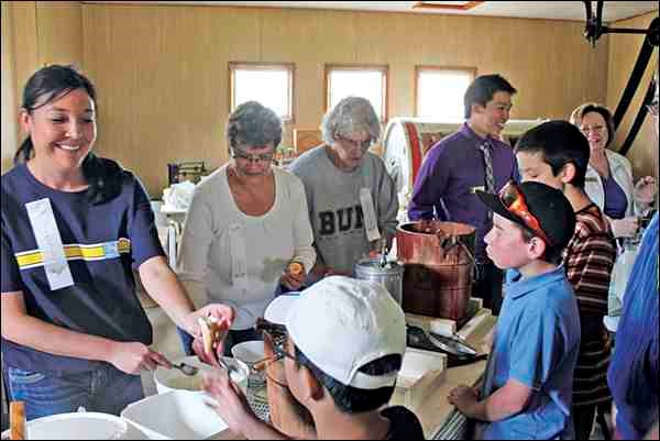 Volunteers from RBC Royal Bank and WDM present a butter and ice cream making demonstration to students during an "RBC Day of Service." Patricia Delainey, RBC staff member, suggested this day of service would be great to do during Museum Days at the Western Development Museum.
