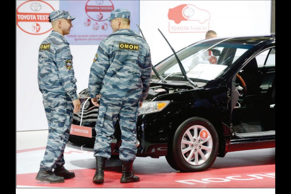 Russian OMON riot police officers look at a Toyota car on the auto salon's opening day in Moscow.