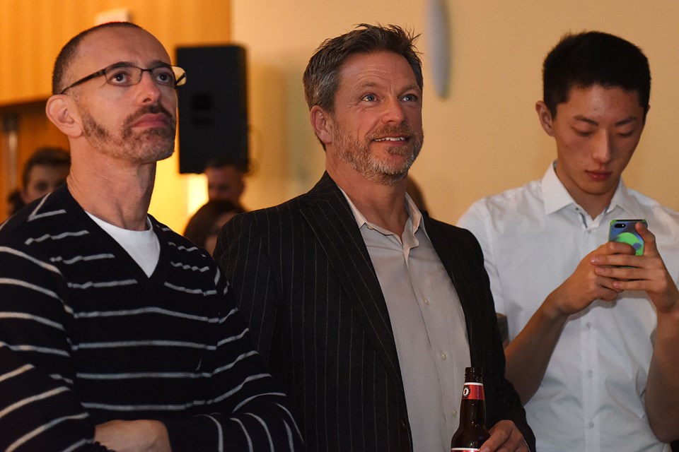 Michael Davis (centre) watches election coverage with friends at the Vision Vancouver party. Photo: Dan Toulgoet