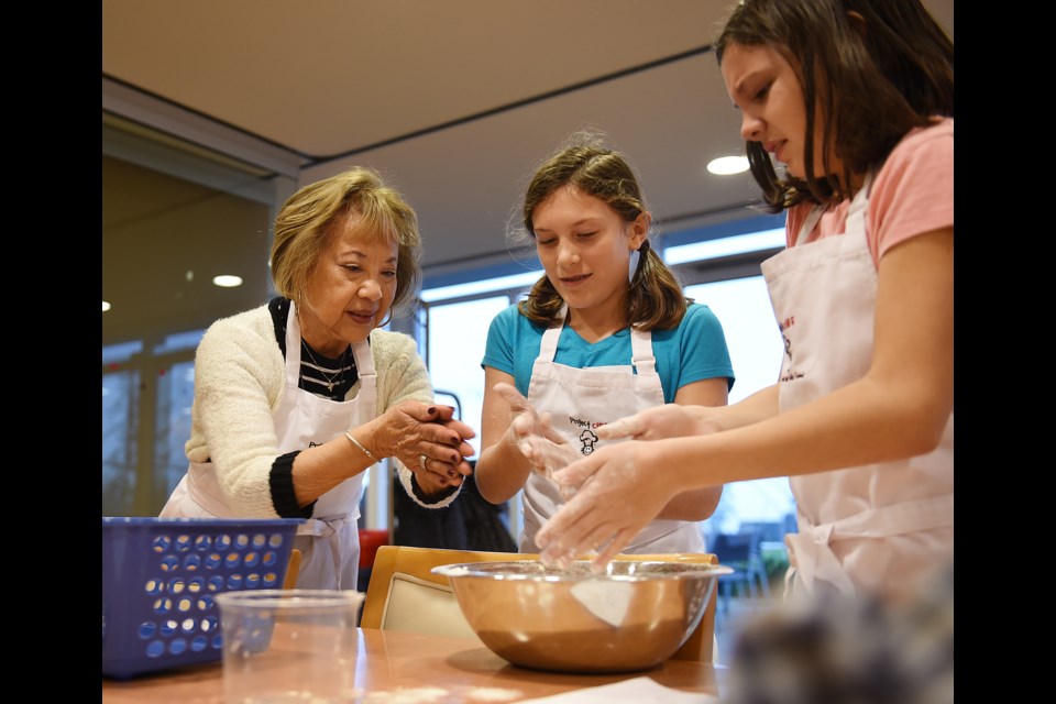 Eleanor Lee mixes biscuit batter with students Loren Eisses (in blue) and Jessica Lee. photo Dan Toulgoet