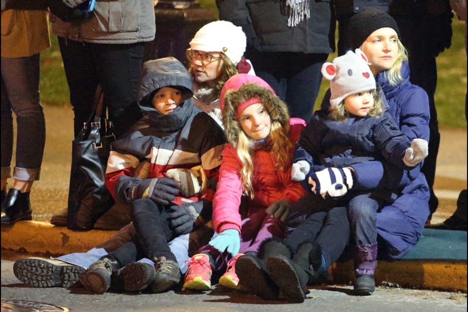 Kristy Abrahams, left, and Melissa Berry watch the floats with their kids Cody Abrahams, 9, Sierra Abrahams, 9, and Cecelia Berry, 2, during the Island Farms Santa Light Parade