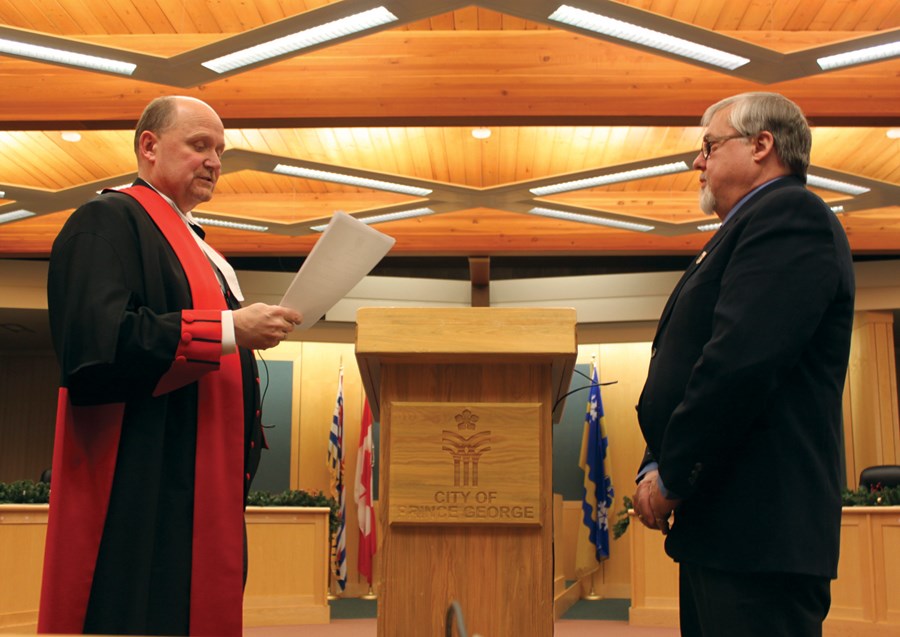 Justice Ron Tindale administers the oath of office to city councillor Frank Everitt at city hall Monday night.