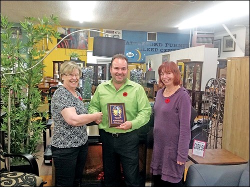 Sharon Powell Welcome Wagon (Saskatchewan) regional manager  presents Battleford Furniture store owner Chris Odishaw with a plaque to acknowledge and honour the business and express appreciation for 20years sponsorship of the Welcome Wagon service in the community. Also in the photo is Jackie Pitman Battlefords representative for Welcome Wagon.