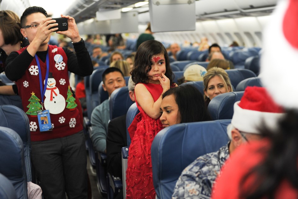 Most of the young passengers aboard the Air Transat flight to the North Pole to find Santa Thursday afternoon peered down aisles and peeked over seats to get a glimpse of the man in the red suit. Photograph by: Rebecca Blissett