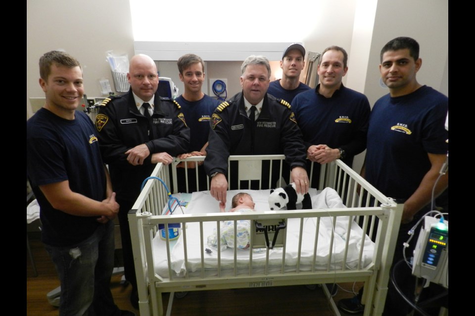 Nice to meet you: Baby Beckett had a visit from New Westminster firefighters on Dec. 19, when they dropped by Royal Columbian Hospital. From left, Trevor Tougas, Rob Dick, Jay Zimmermann, Fire Chief Tim Armstrong, Ryan Blatter, Glen Bailey and Joga Hayre.