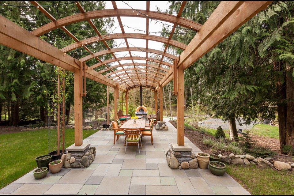The long, elegant, arched pergola over a stone-flagged terrace makes a great setting for an outdoor dining and seating space. There's a wood-fired pizza oven at the far end.