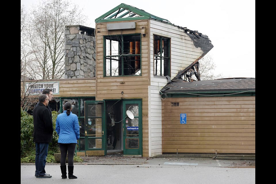 Marine Pub and Brewhouse owners Pal Singh, in black coat, and Jasmine Saini, in blue, look upon the damage done by a three-alarm blaze, which destroyed the pub early Saturday morning.