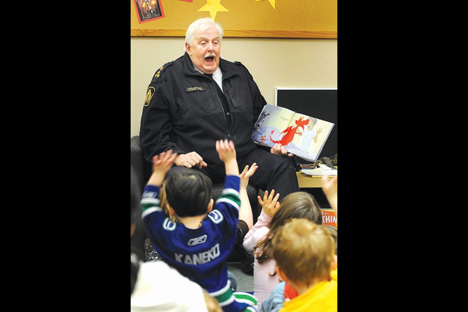 Chief Jim Cessford reads to a group of children at Ladner Pioneer Library during Family Literacy Day in 2012. He got an enthusiastic response when he asked the kids who wanted a pet dragon.