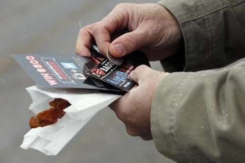 Dale Mottram checks for a winner of his free scratch-and-sniff bacon-scented scratch ticket Friday Jan. 30, 2015 at the welcome center in Hooksett, N.H. To promote sales of the new $1 lottery ticket officials gave free smoked bacon samples and tickets at the rest stop.