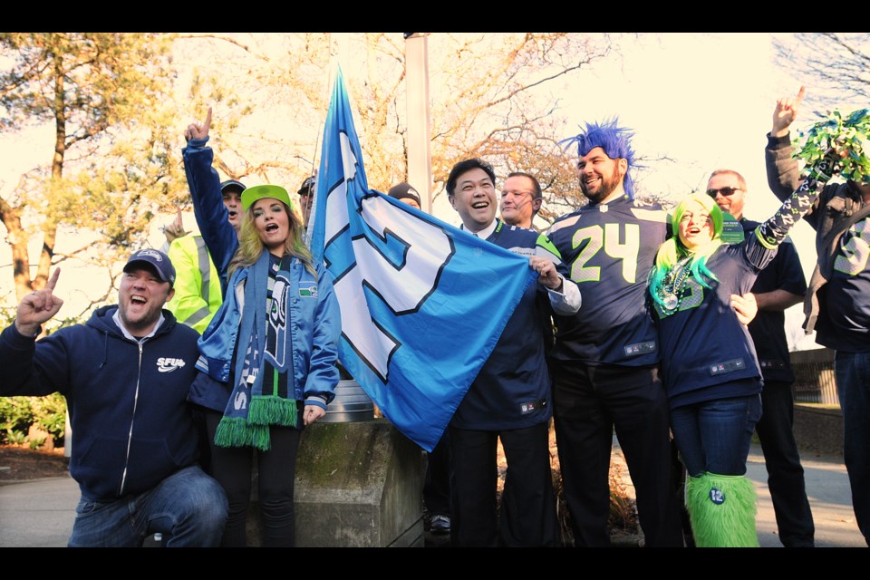 Vancouver city councillor Kerry Jang and Seattle Seahawks supporters raised the 12th Man flag at Vancouver city hall on Jan. 30, 2015. photo Dan Toulgoet