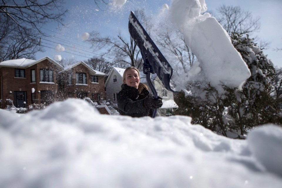 Lucy Jackson, a recent arrival from Britain, shovels snow outside her home in Toronto on Monday. The mother of two is experiencing her first Canadian winter and is shovelling for only the second time in her life.