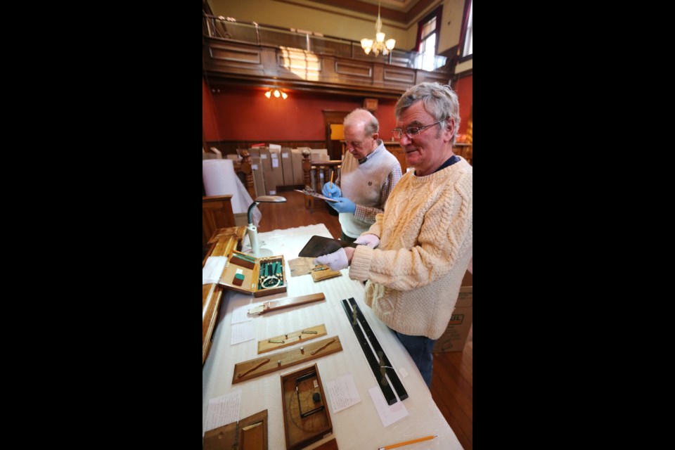 Bob George, left, and Tom Mace catalogue a roller ruler. Museum officials hope to move into the CPR Terminal building on the Inner Harbour.