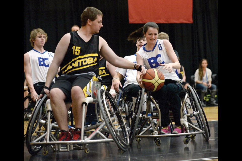Team BC Paula Higgins with the ball and Team Manitoba Kurtis Wiens trying to strip it from her in a wheelchair basketball game Monday at Duchess Secondary school during the Canada Winter Games.