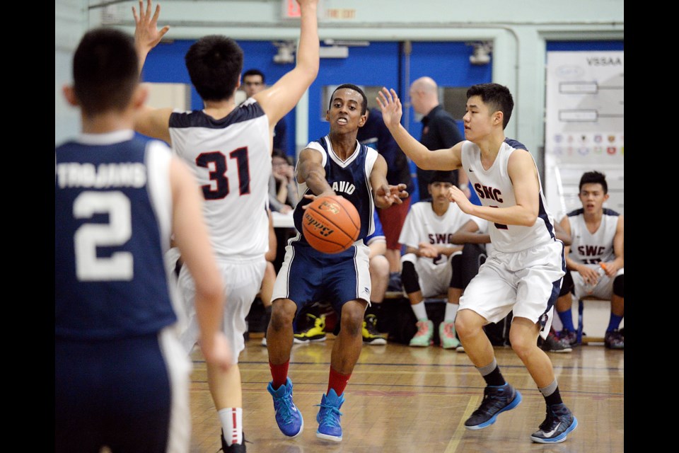 Trojan Alula Berhe (No. 9) passes the ball past Bulldogs Harry Lui (No. 31) and David Huang (No. 2) and in the senior boys AAAA Vancouver city championship final at home Feb. 13, 2015. Churchill beat David Thompson 97-65. Photo Jennifer Gauthier