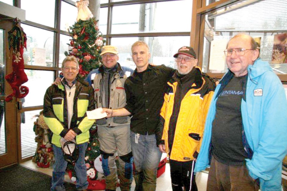 The Time Travellers Motorcycle Club presents an $850 cheque to the Lookout Emergency Aid Society. At every club meeting, members put a few dollars into a wooden box. They open it up at their Christmas lunch and donate the contents to a worthy cause.