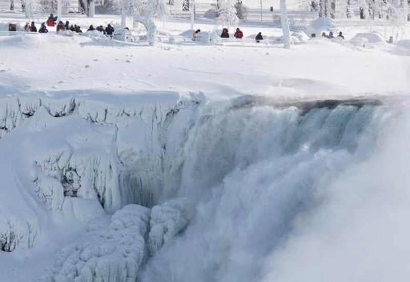 Niagara Falls State Park visitors look over masses of ice formed around the American Falls, photographed from across the Niagara River in Niagara Falls, Ont., Thursday, February 19, 2015.