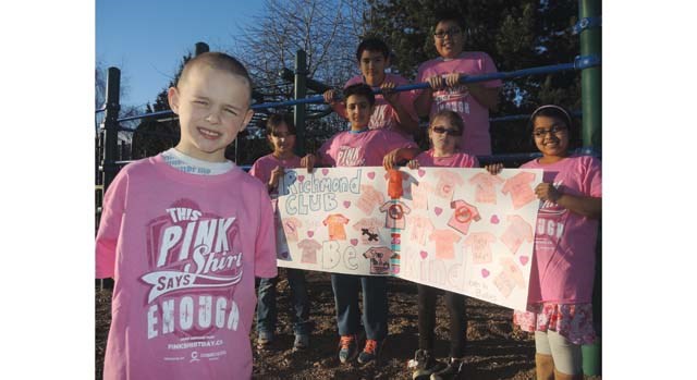 Iain, 5, and his fellow Boys and Girls Club member, who meet four times a week at Mitchell elementary, show off their Pink Shirt Day banner