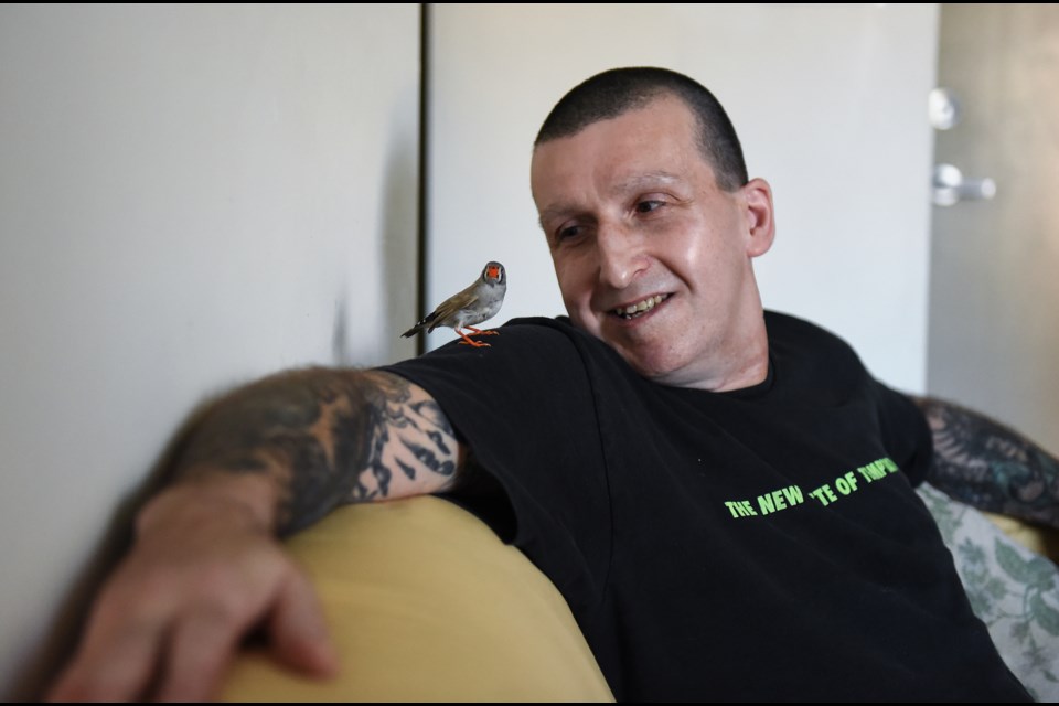 Roy Mackintosh sits on his living room couch with Squirt, a finch he hand-raised from a baby. Squirt is one of many finches that live in Mackintosh’s small apartment in the Downtown Eastside. Photo Rebecca Blissett