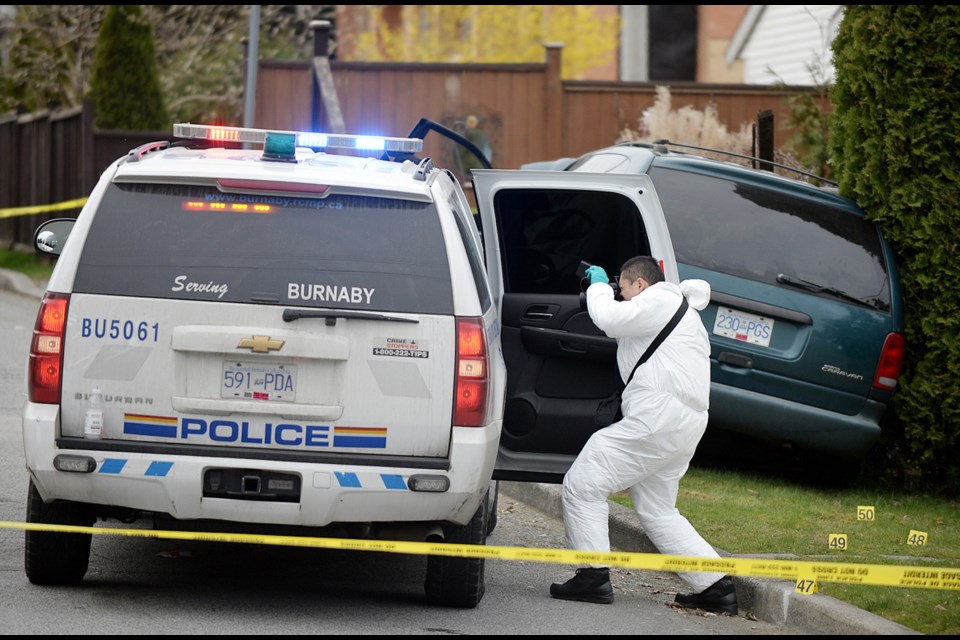 An Independent Investigations Office of B.C. investigator collects evidence after a police-involved shooting near Canada Way and Edmonds Street in Burnaby on March 1, 2015.