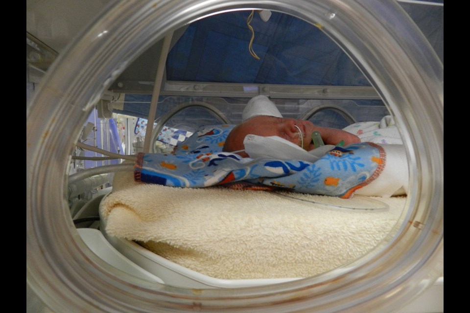 The blue blanket beneath this baby is an example of a snug blanket. Snug blankets are given to moms of babies admitted to RCH's neonatal intensive care unit. The moms sleep with the blankets to transfer their scent. The blankets are then given back to the babies to help form a bond with their mothers through the scent.