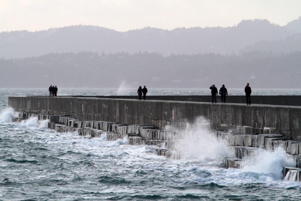 People stroll along the breakwater where there is now no railing to stop someone from falling into the water.