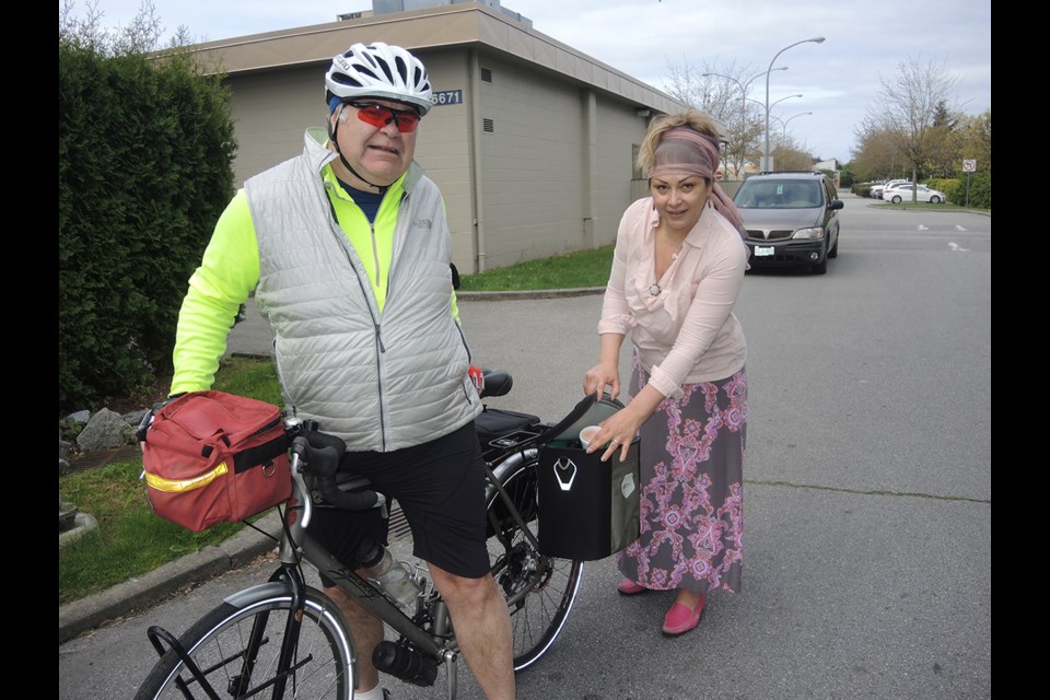 Ecaterina Grisacova, who works for the Richmond Society for Community Living, assists Keith Lang with his meals on bikes delivery. Grisacova is also a volunteer for Meals on Wheels, a program that assists shut-ins with a healthy meal and a friendly visit. May, 2015.